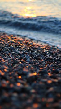 Close-up of pebbles reflecting sunset light on a Calabrian beach.