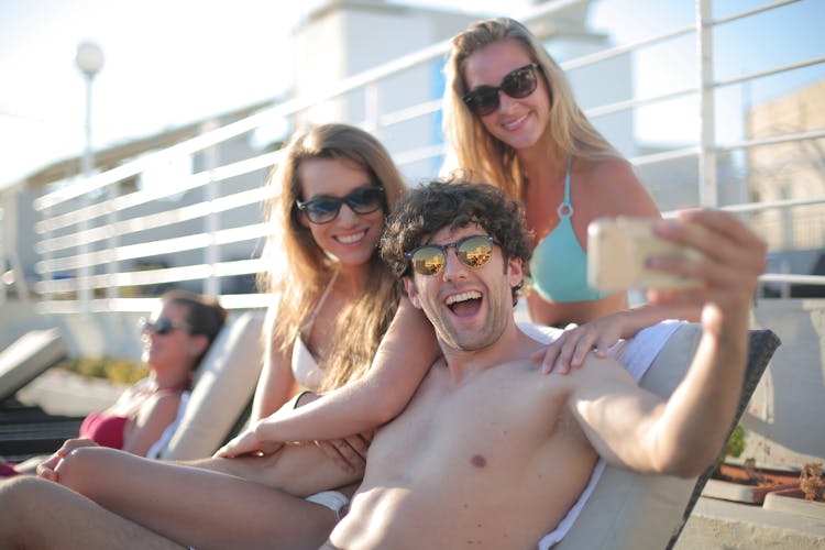 Joyful Friends Taking Video On Phone While Resting On Beach