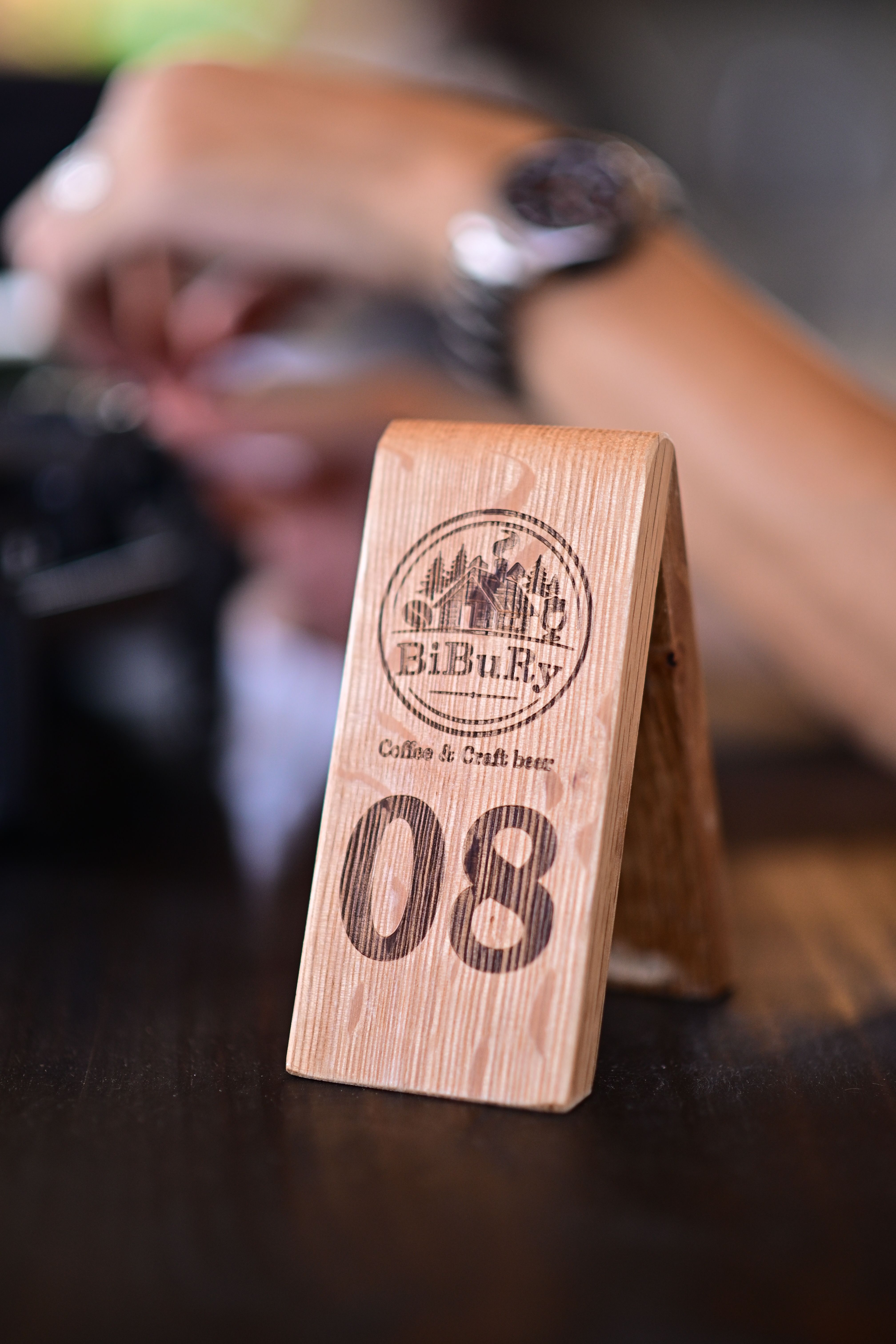 Close-up of a wooden table number sign in a cafe with blurred background.