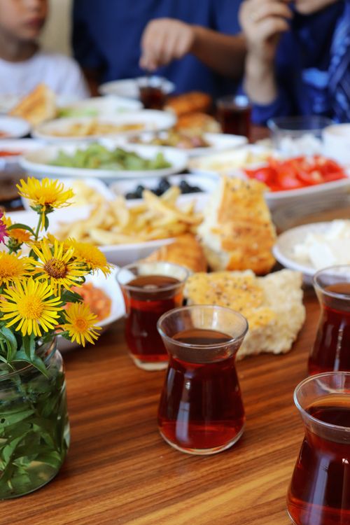 Free A vibrant spread of Turkish breakfast items with traditional tea and fresh flowers on a wooden table. Stock Photo
