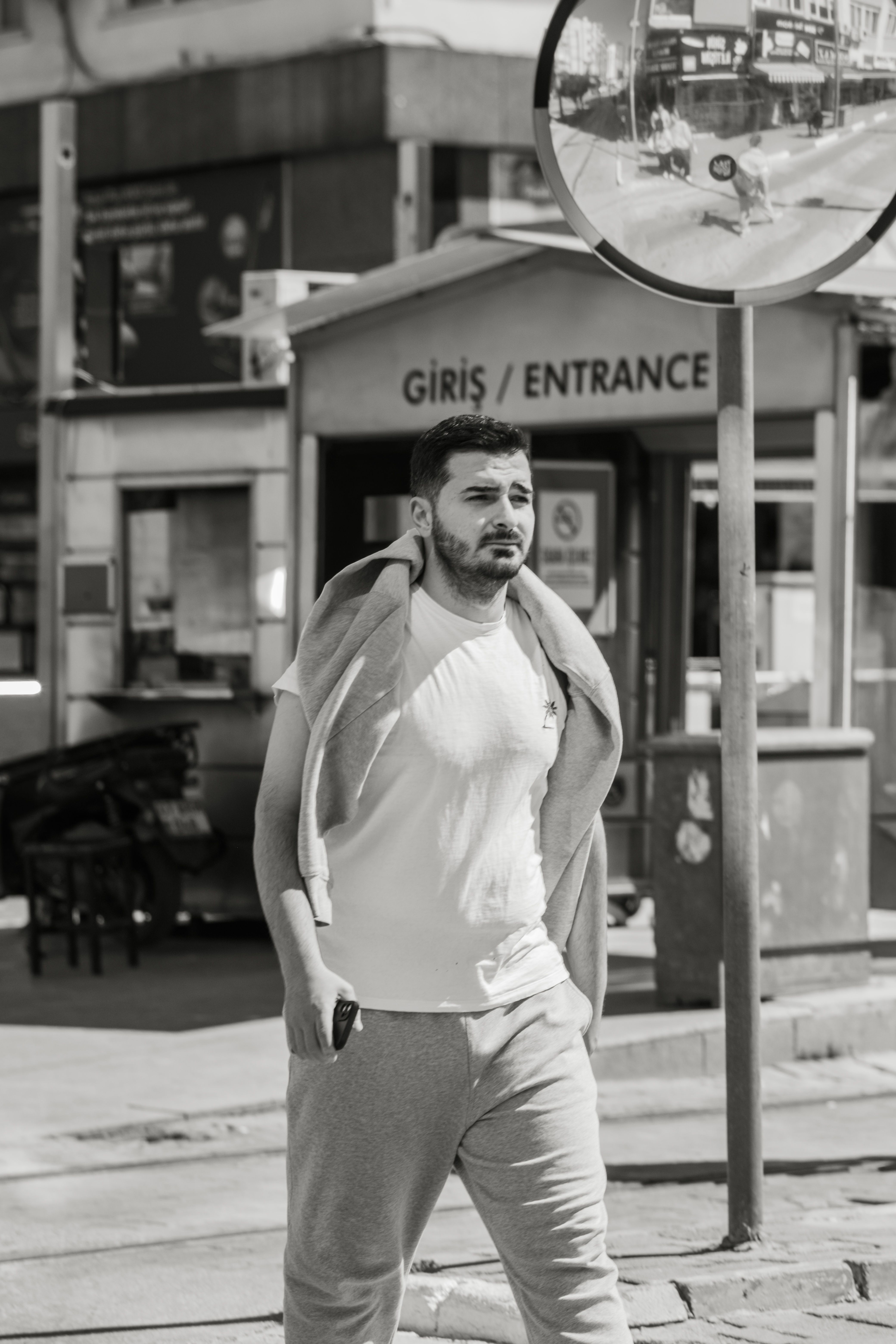 Man walking casually in urban setting, captured in black and white.