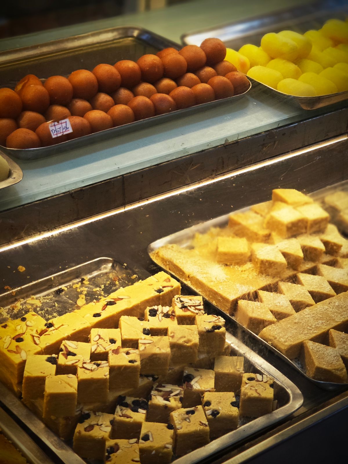 Assorted traditional Indian sweets on display in a shop, representing Dharwad's GI-tagged pedha confectionery trade