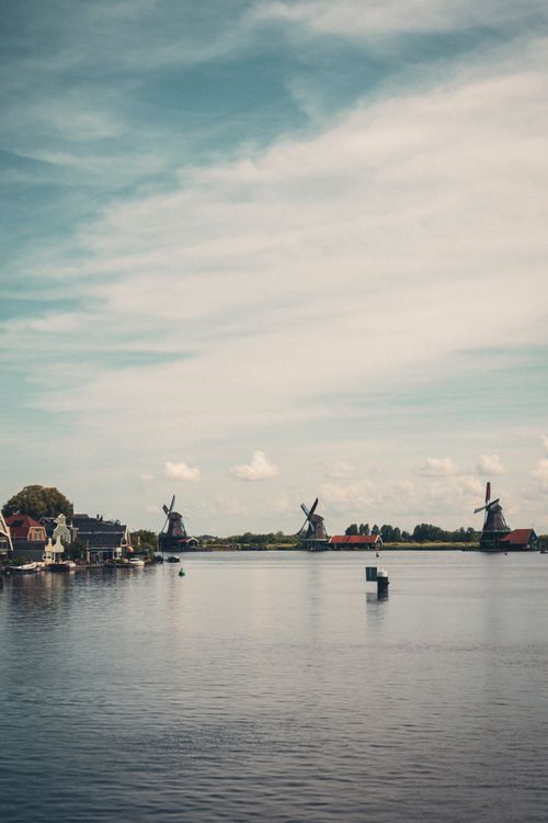 Free Picturesque view of traditional windmills and houses by the water at Zaanse Schans, Netherlands. Stock Photo