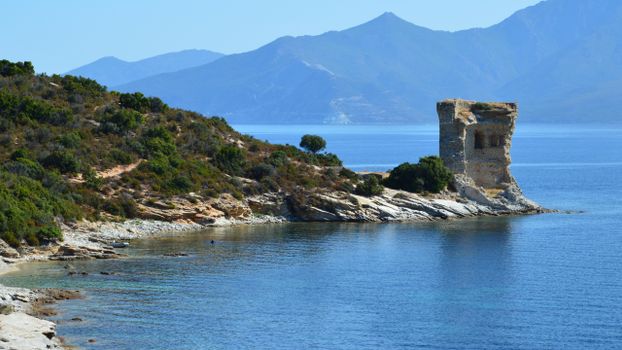 Tranquil coastal scenery with historic Genovese tower overlooking the Mediterranean Sea in Saint-Florent, Corsica.