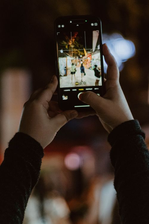 Free Hands holding a smartphone capturing nightlife scene in Malay, Philippines. Stock Photo