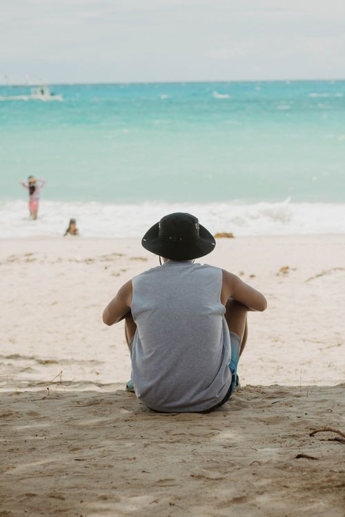 Free A man enjoys the tranquil view of Puka Beach's white sand and turquoise waters. Stock Photo