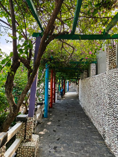 Free Explore a colorful pathway lined with vibrant flora and unique pebble walls in Bình Thuận, Việt Nam. Stock Photo