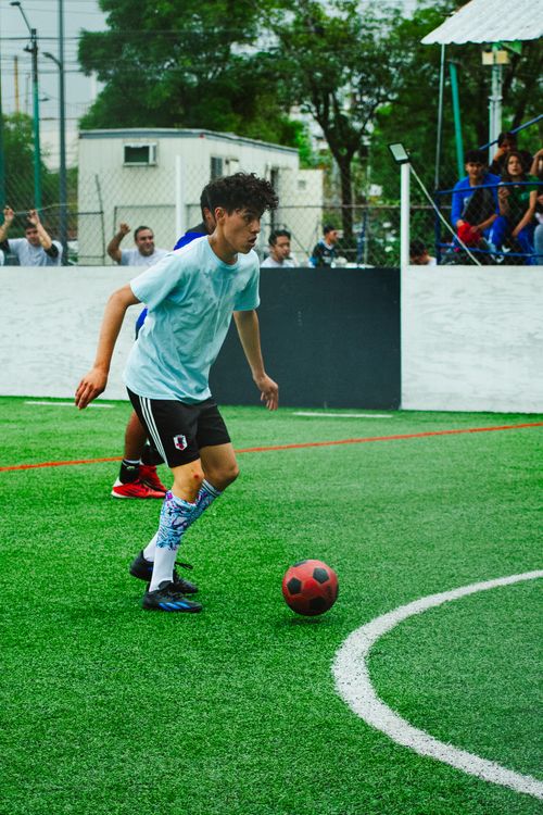 Free Young footballer dribbles during a vibrant match in Mexico City. Energetic sports atmosphere. Stock Photo