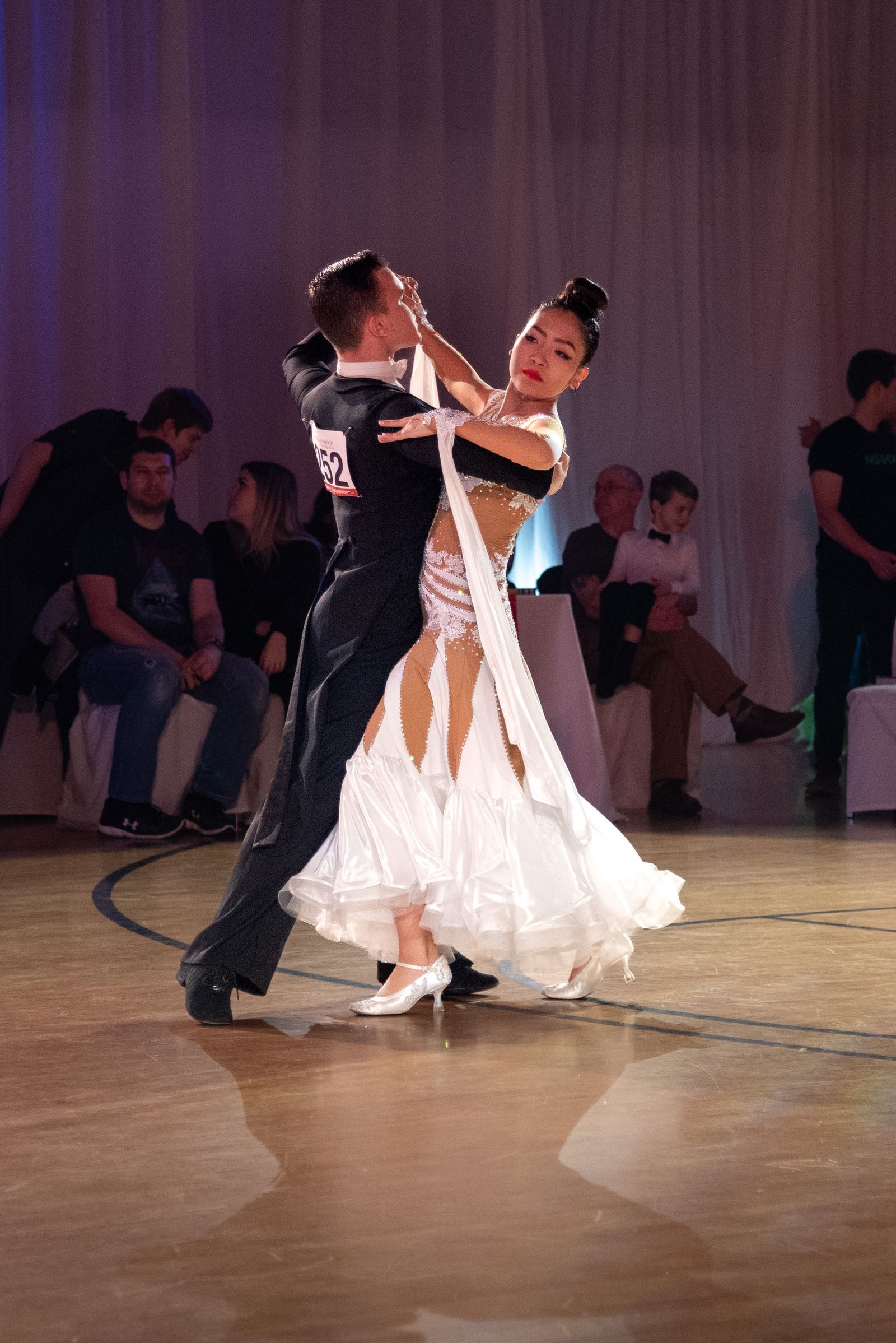 Ballroom — competition couple in formal attire on a warm-lit floor.