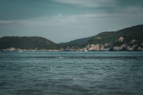 Free Tranquil coastal scene in Zihuatanejo, Mexico, featuring lush green hills and calm blue waters. Stock Photo