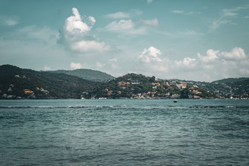 Free Beautiful landscape of Zihuatanejo Bay with lush hills and clear waters under a cloudy sky. Stock Photo