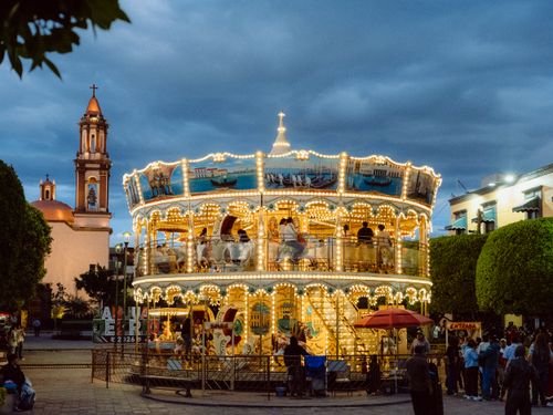 Free A vibrant night scene featuring a dazzling Venetian carousel with a church backdrop in San Juan del Río, Mexico. Stock Photo