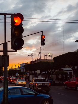Street scene with traffic lights and cars during sunset in a Mexican city.