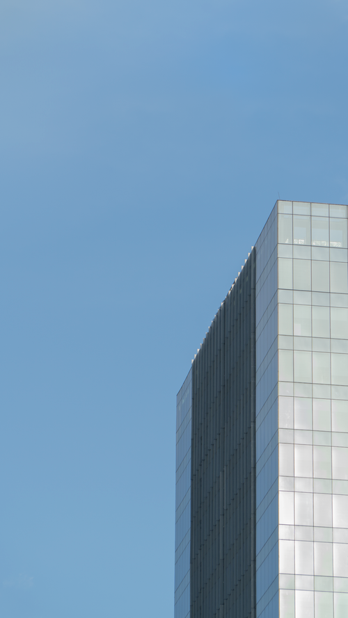 Free A sleek glass skyscraper under a clear blue sky, minimalist design. Stock Photo