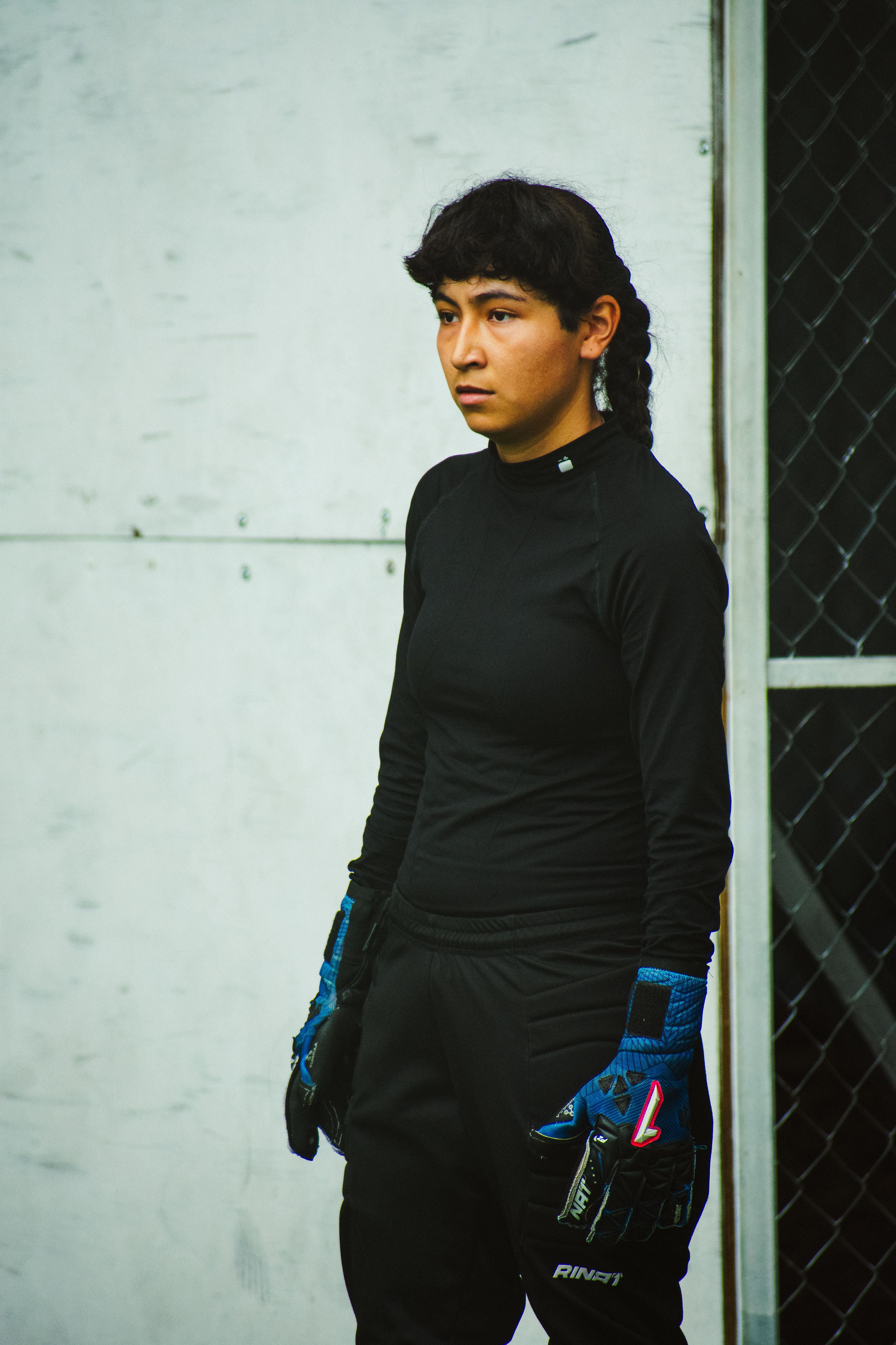 Young female goalkeeper in black sportswear and gloves on a field in Mexico City.