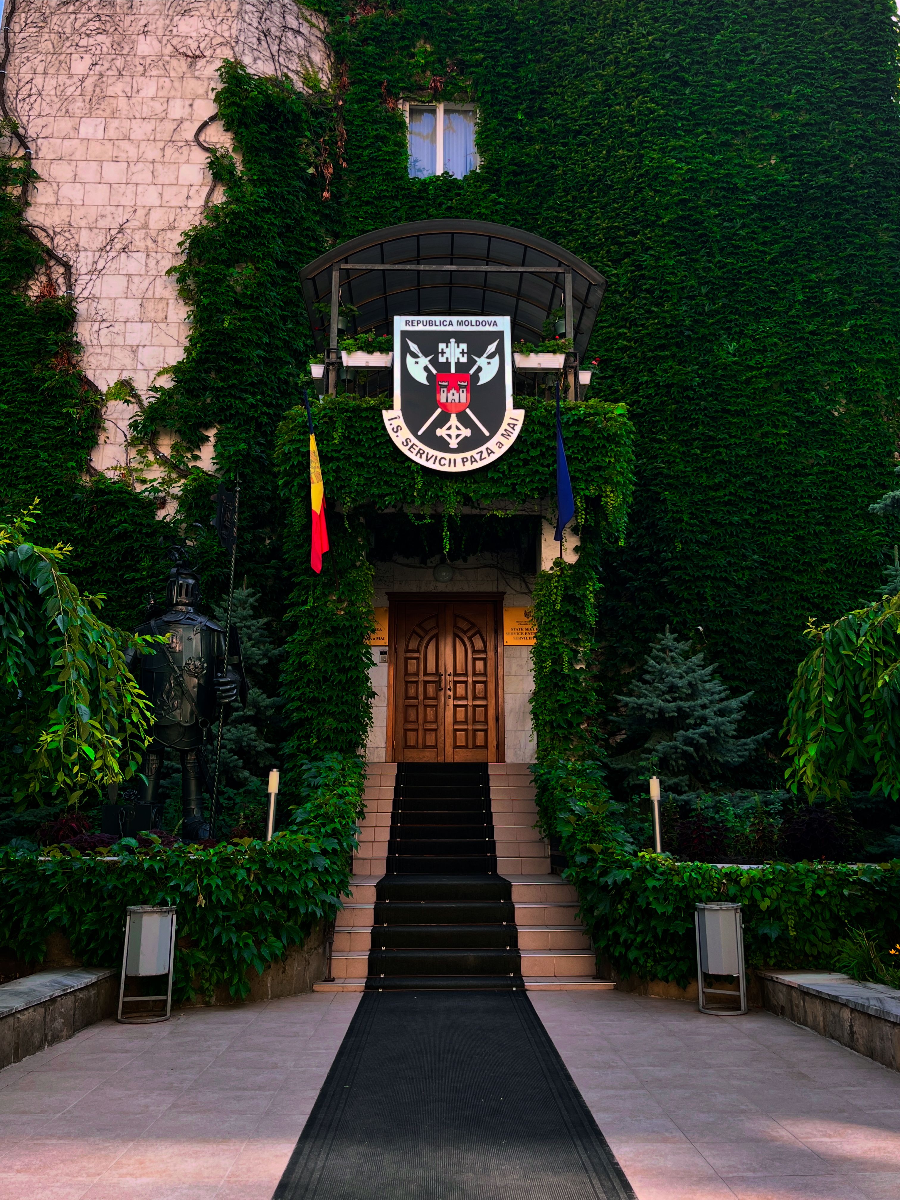 Entrance to a historic building in Chisinau, Moldova, adorned with ivy and national flags.