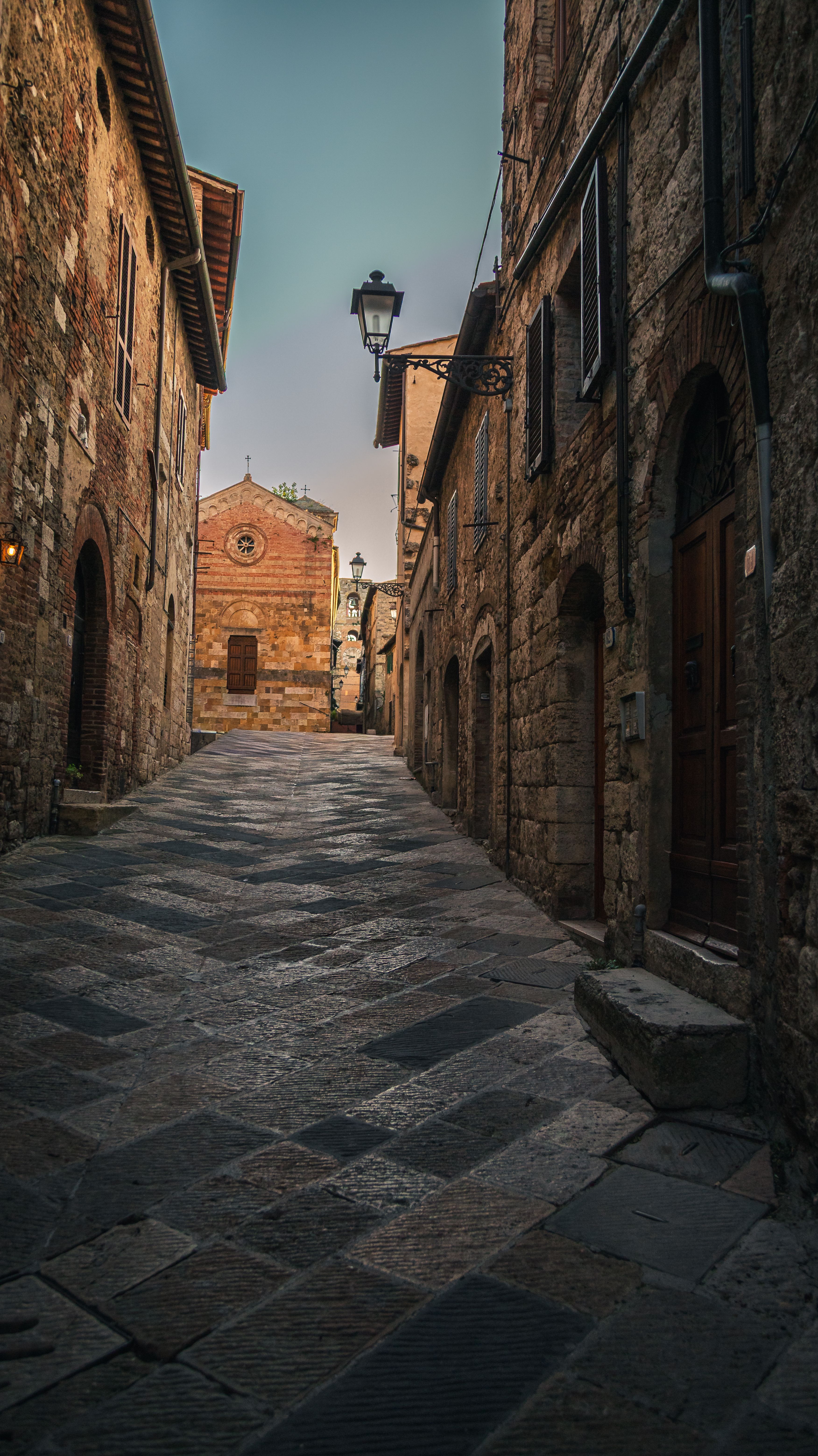 Explore the picturesque medieval alley in Pienza, Tuscany with stone buildings and rustic charm.