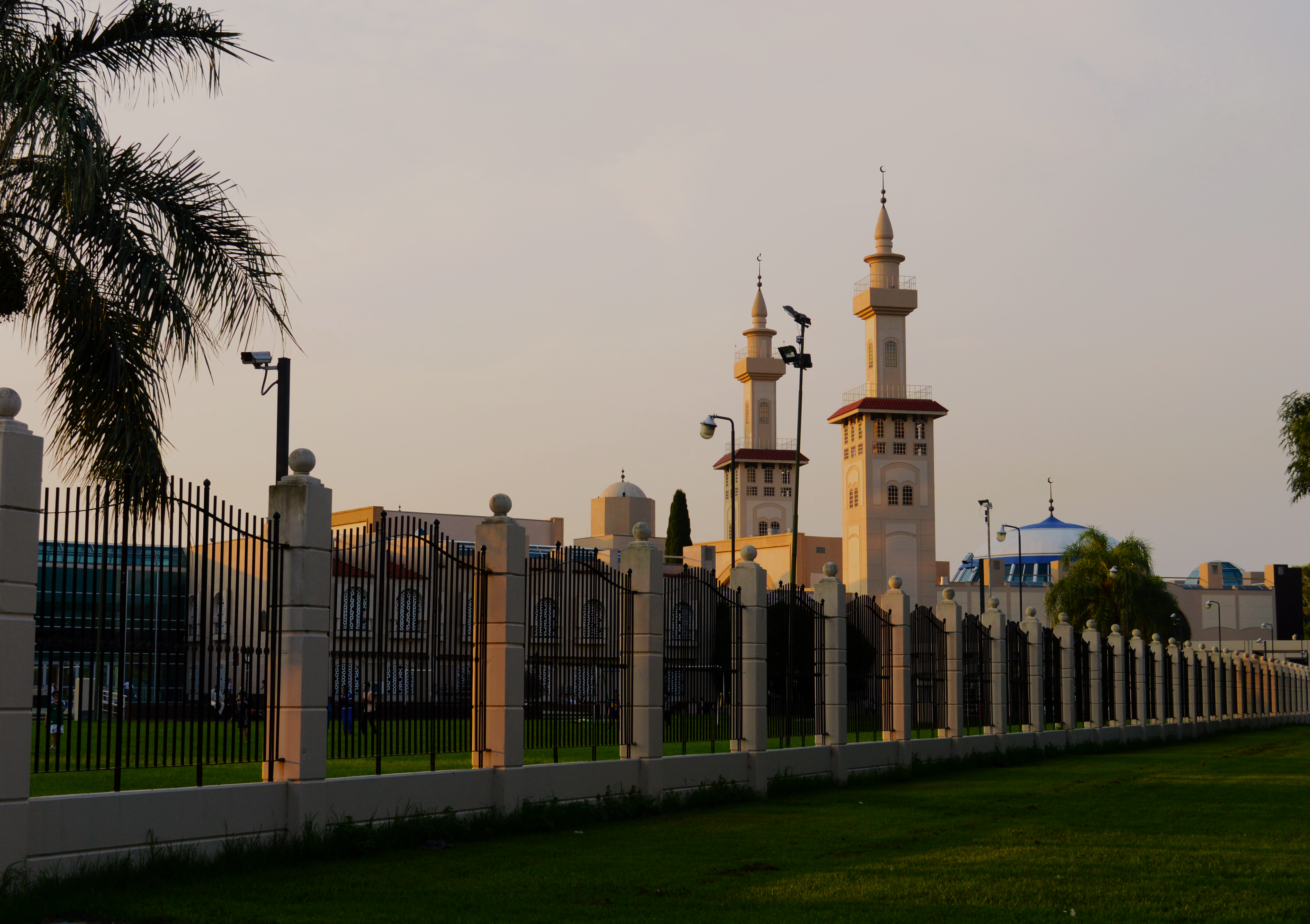 A beautiful sunset over an Islamic cultural center in Buenos Aires with minarets and palm trees.