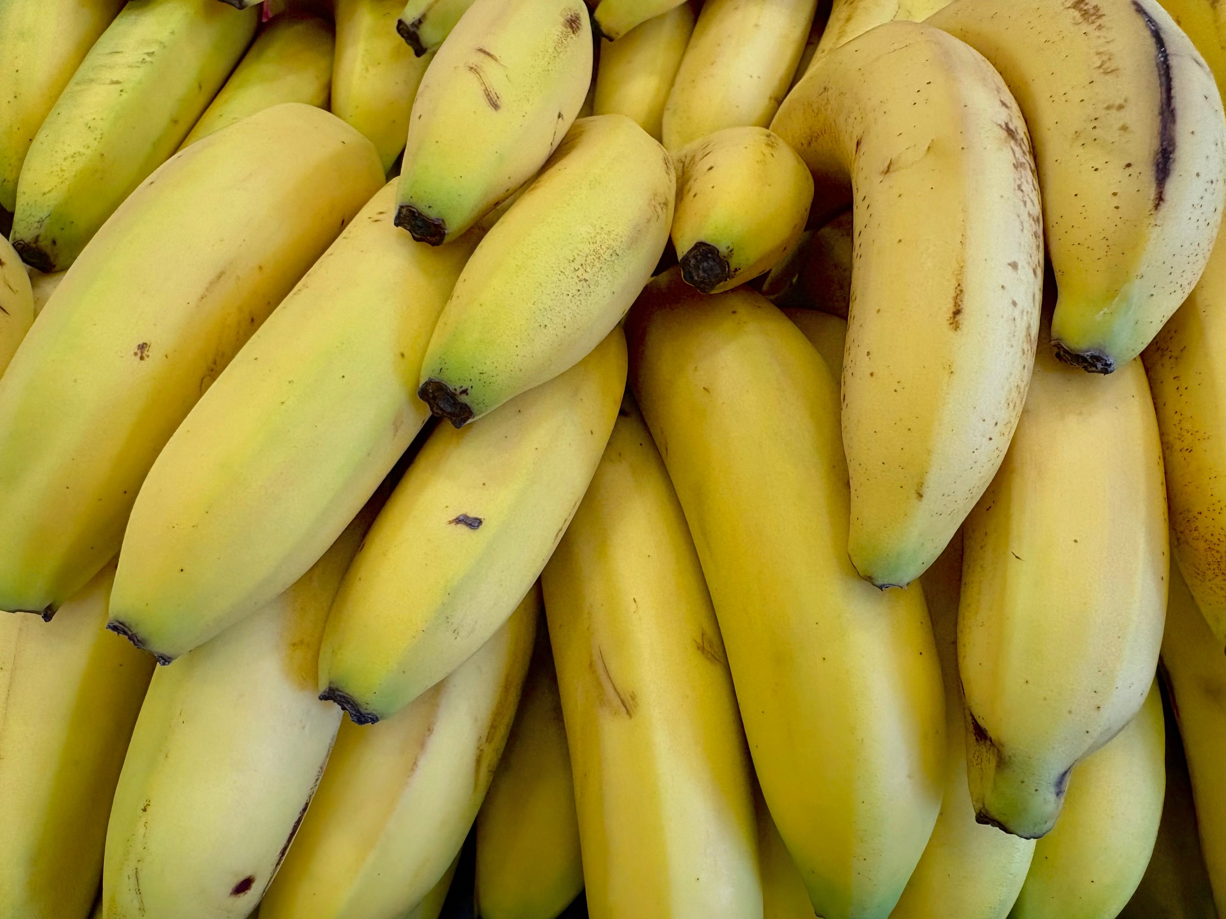 A person holding a bunch of bananas while shopping at a grocery store produce section