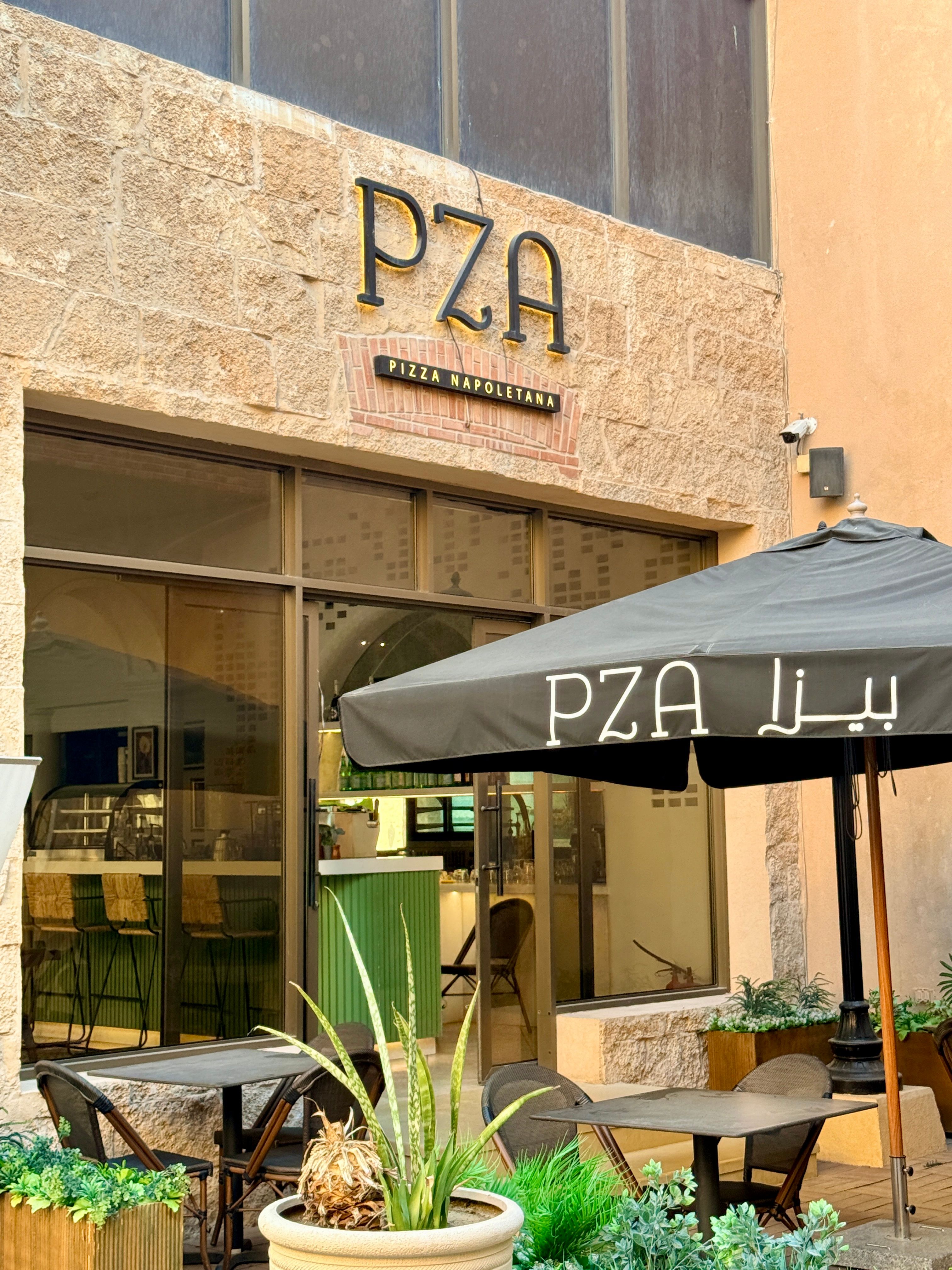 Charming outdoor seating at PZA Pizza Napoletana restaurant, offering a cozy ambiance with stylish umbrellas.
