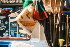 Local market stall showcasing brooms, buckets, and sugar sacks in vibrant sunlight.