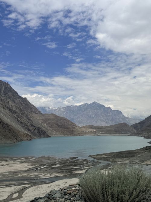 Free Breathtaking view of a turquoise lake surrounded by rugged mountains under a partly cloudy sky. Stock Photo