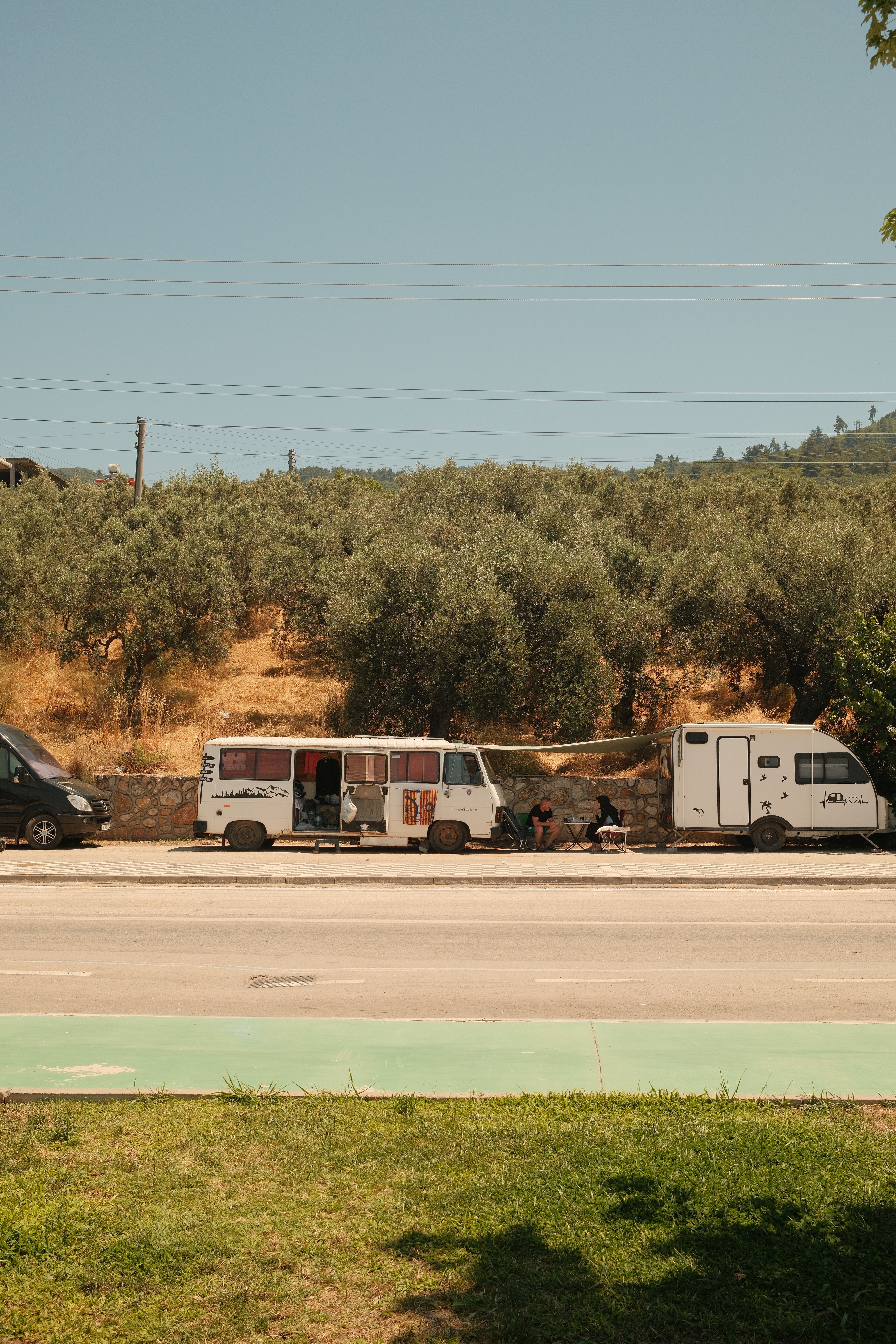 Camper vans parked by olive grove in Bursa, Türkiye during a sunny day.