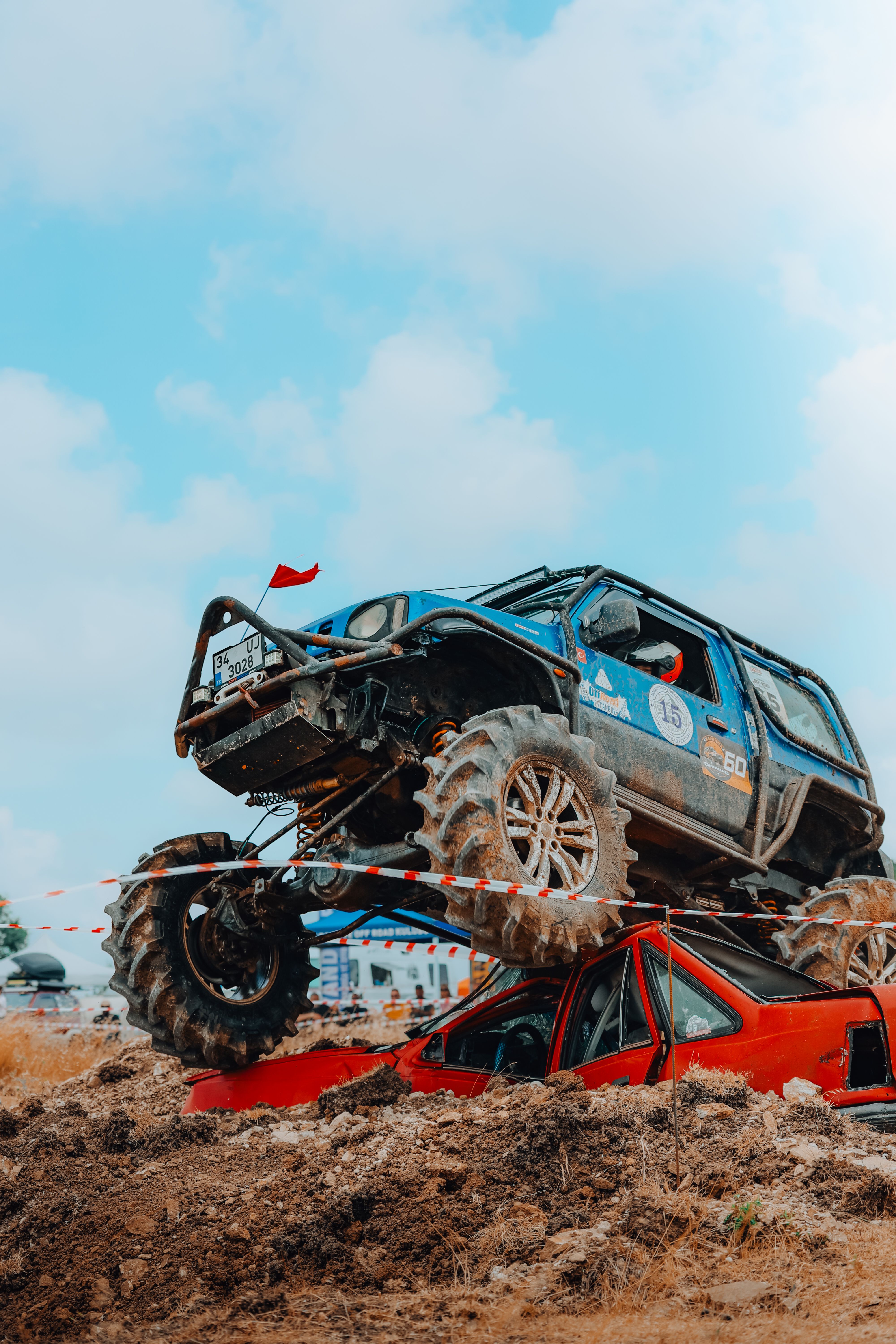 Dramatic off-road scene with a blue jeep crushing a red car in an action-packed rally event.