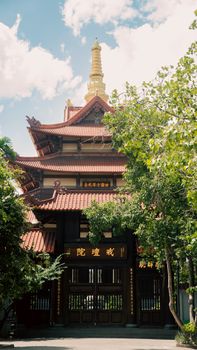 Traditional Asian pagoda with ornate details and lush greenery in Ho Chi Minh City, Vietnam.