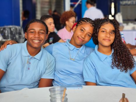 A group of teenagers smiling together in blue school uniforms at an indoor event.