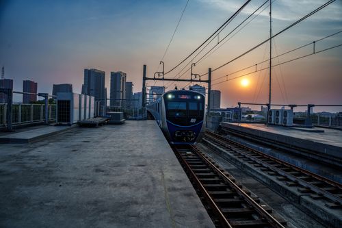 Free A metro train arrives at a rooftop station in Jakarta, Indonesia during a vibrant sunset. Stock Photo
