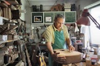 Focused craftsman working on guitar in workshop