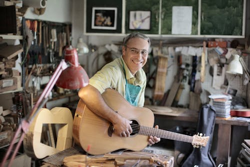 Man in Yellow Polo Shirt Playing Acoustic Guitar