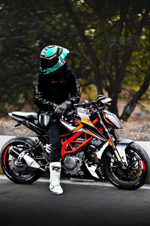 Free A motorcyclist in full gear poses with a sporty motorcycle on a tree-lined road. Stock Photo