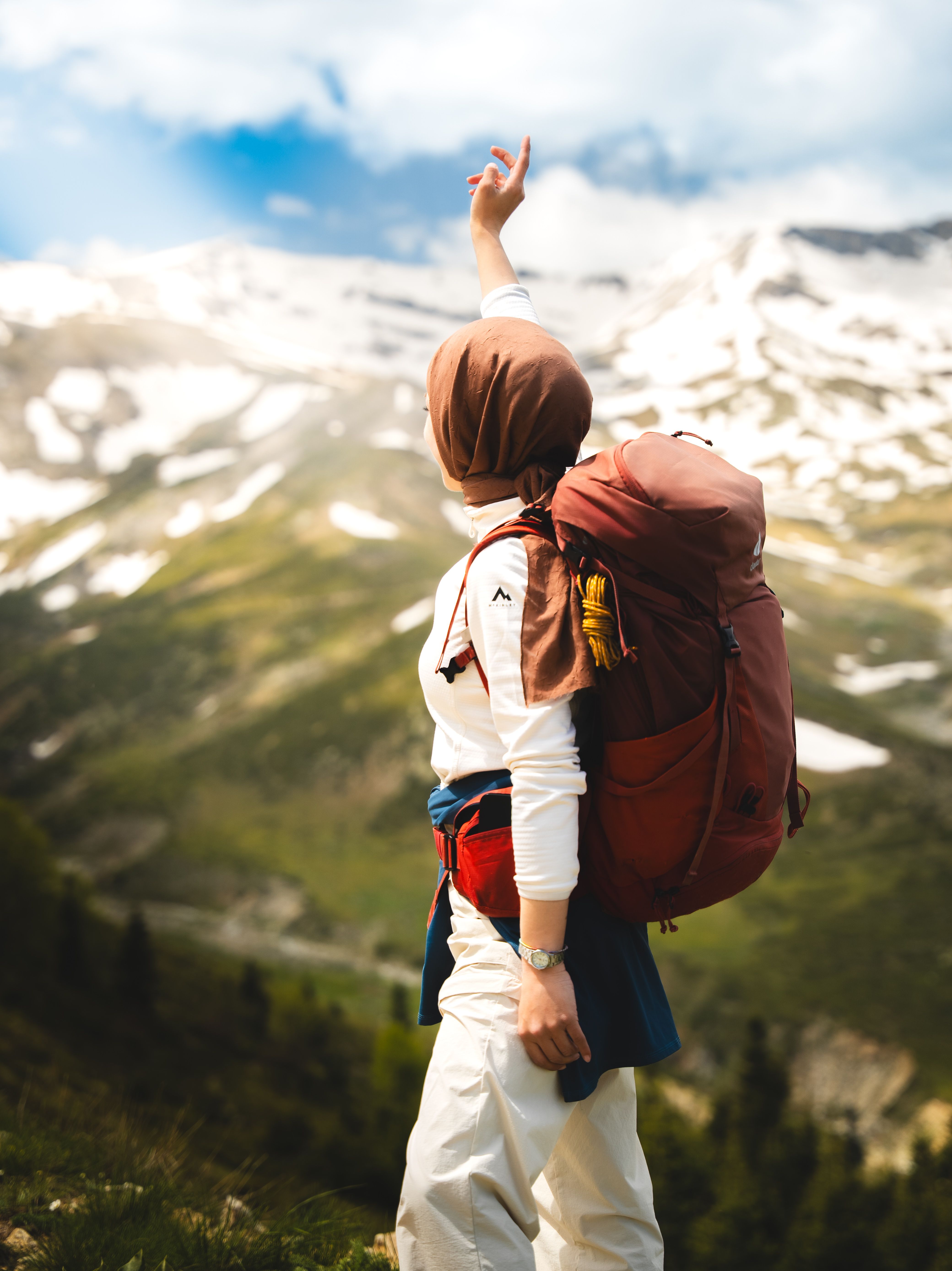 Explore the thrill of mountain hiking with a lone hiker reaching towards snowy peaks in a breathtaking landscape.