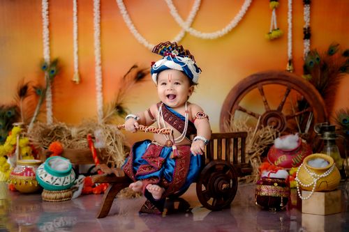 Free Adorable baby in vibrant Indian clothing celebrating Janmashtami with cultural props. Stock Photo