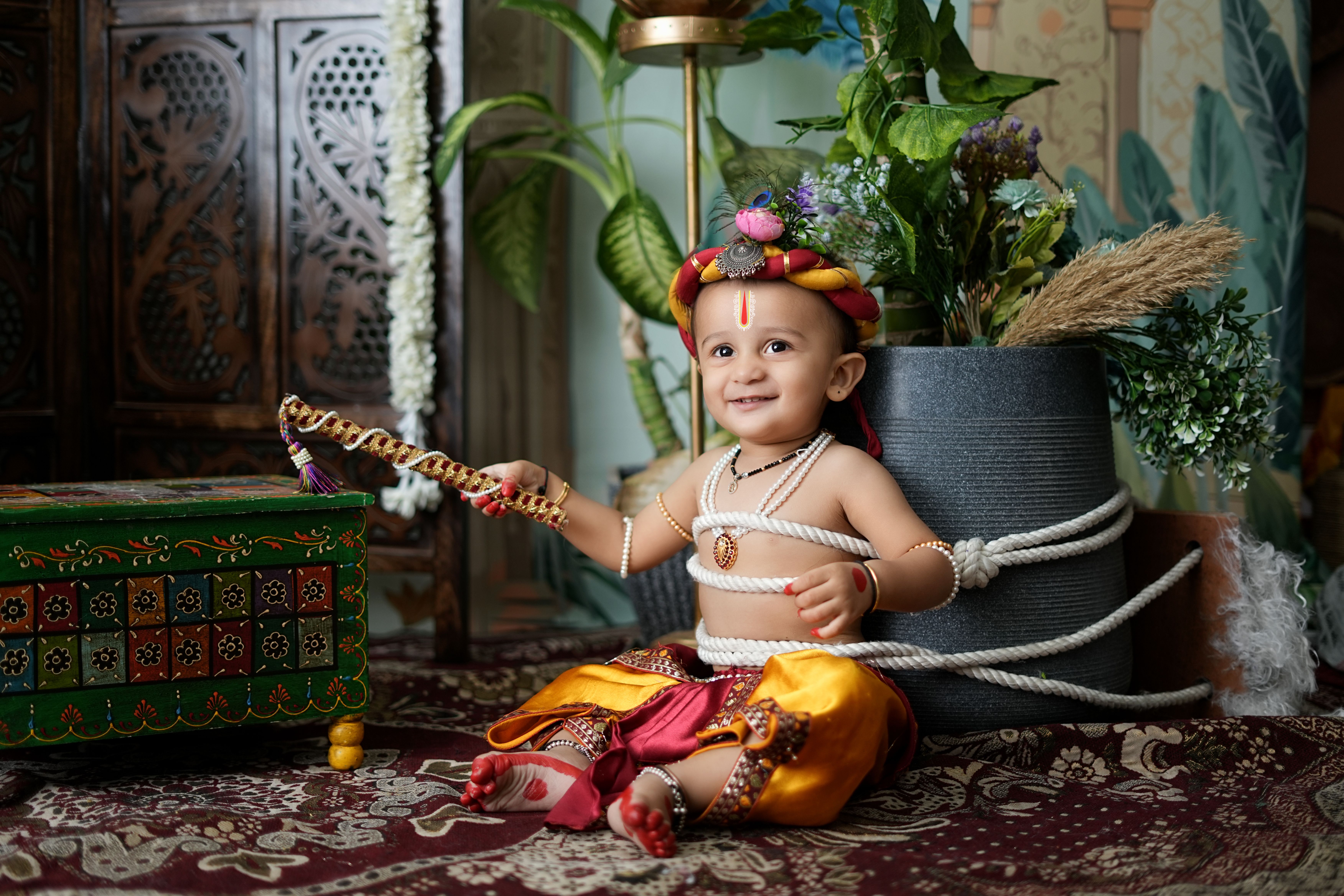 Adorable baby dressed in colorful traditional Indian attire, smiling indoors.