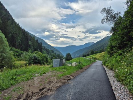 Picturesque view of a mountain road surrounded by lush greenery in Trentino-Alto Adige, Italy.