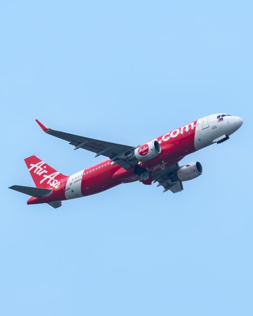 Free AirAsia Airbus A320 soaring through the blue sky over Sepang, Malaysia, highlighting travel and aviation. Stock Photo
