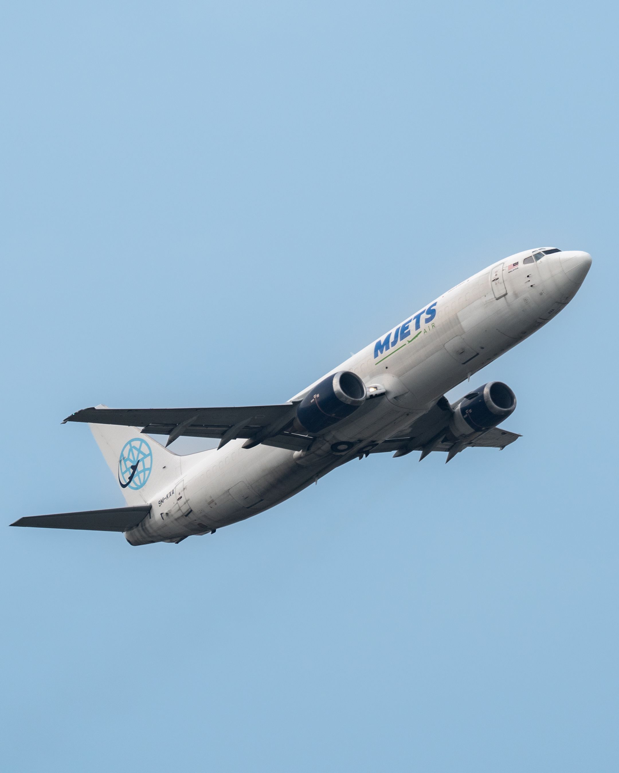 A commercial airplane takes flight over the clear blue sky in Sepang, showcasing aviation dynamics.