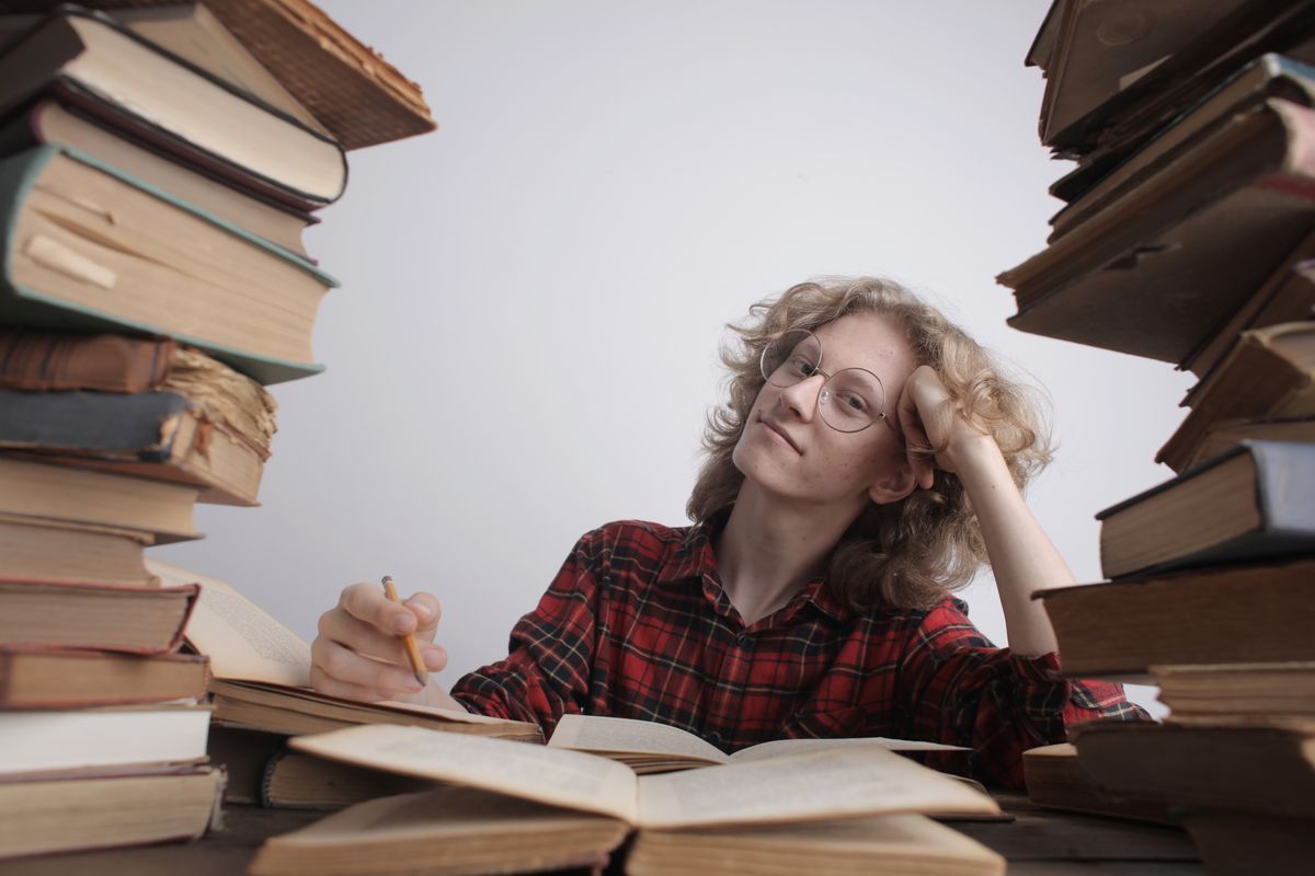 A young woman studying intensely surrounded by large stacks of books in a library setting
