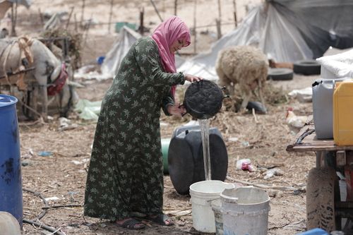 Free A woman in Gaza collects water in a rural setting, showcasing daily life challenges. Stock Photo