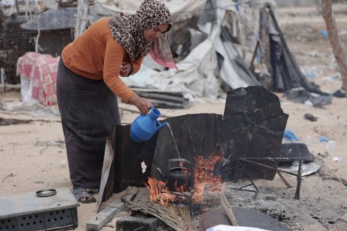 Free Middle Eastern woman cooking over open fire in rural area. Stock Photo