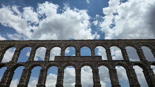 Free Historic Segovia Aqueduct arches silhouetted against a dramatic cloudy sky. Stock Photo