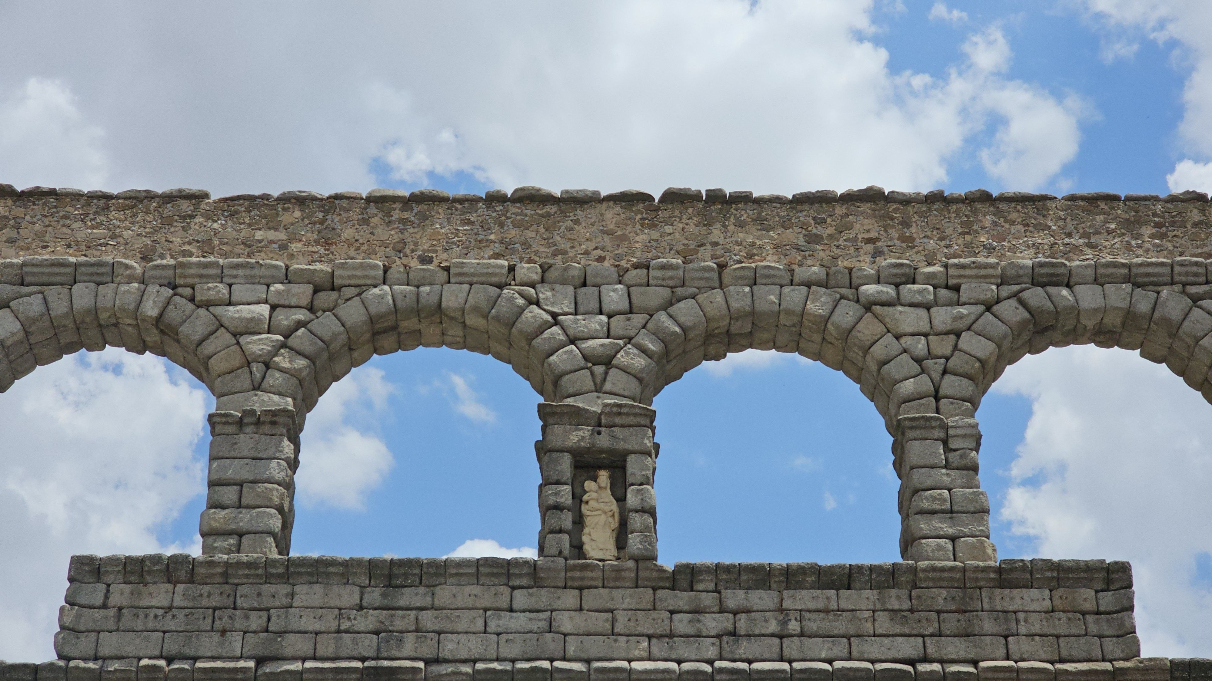 Budget traveler walking near Segovia aqueduct with backpack