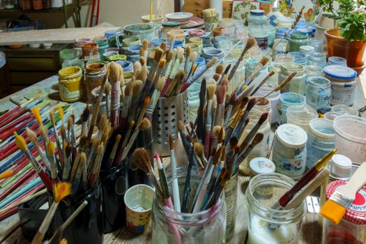 Colorful assortment of paintbrushes and jars in a lively artist's studio.