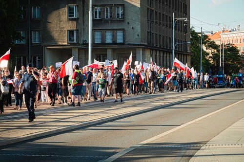 Free People marching in Wrocław with Polish flags honoring historical events. Captured in daylight. Stock Photo