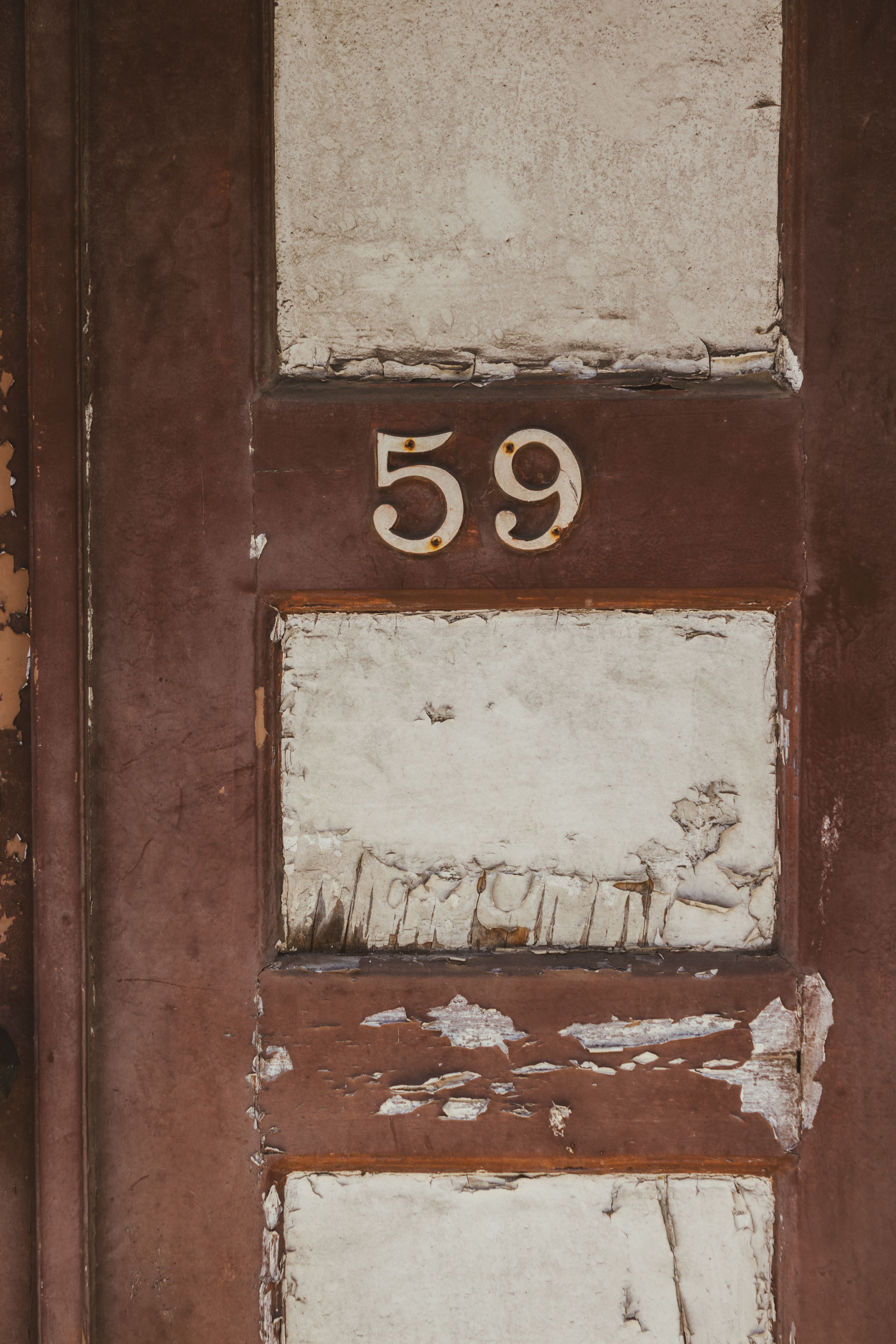 Detailed shot of an old wooden door with peeling paint, number 59 adds vintage appeal.