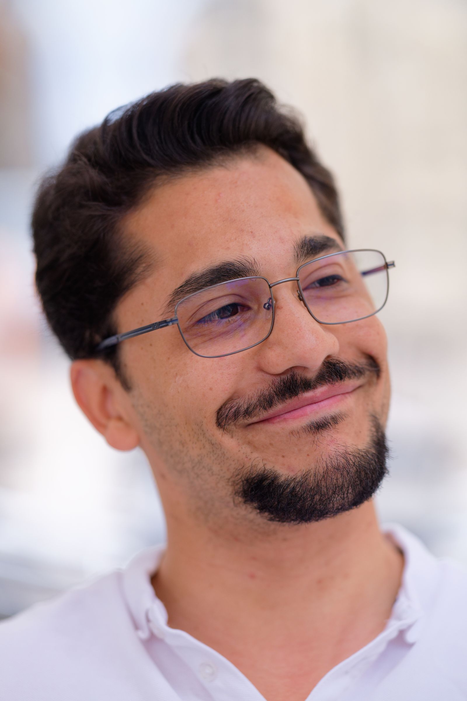 Portrait d'un homme assuré, lunettes et barbe, souriant en extérieur