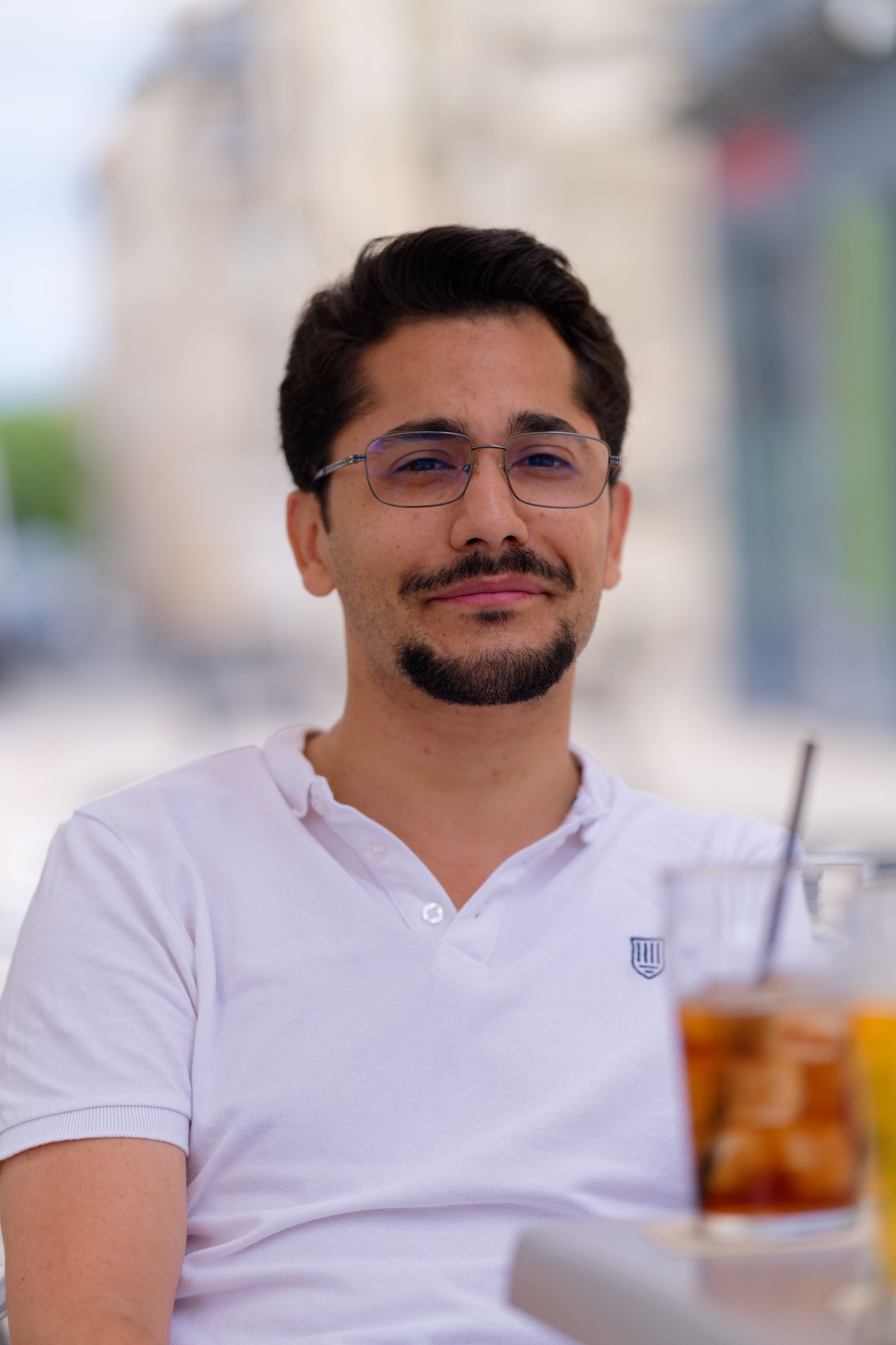 Man enjoying a refreshing drink at an outdoor café with a relaxed vibe